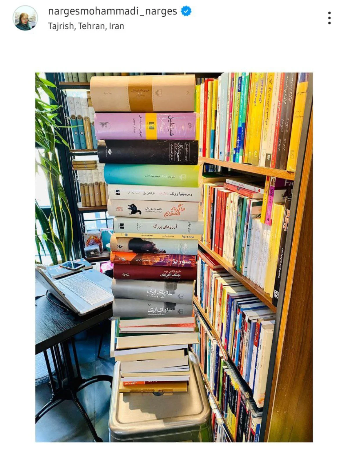 کتابخانه چوبی نرگس محمدی و علی اوجی که کنار گلدان و میز