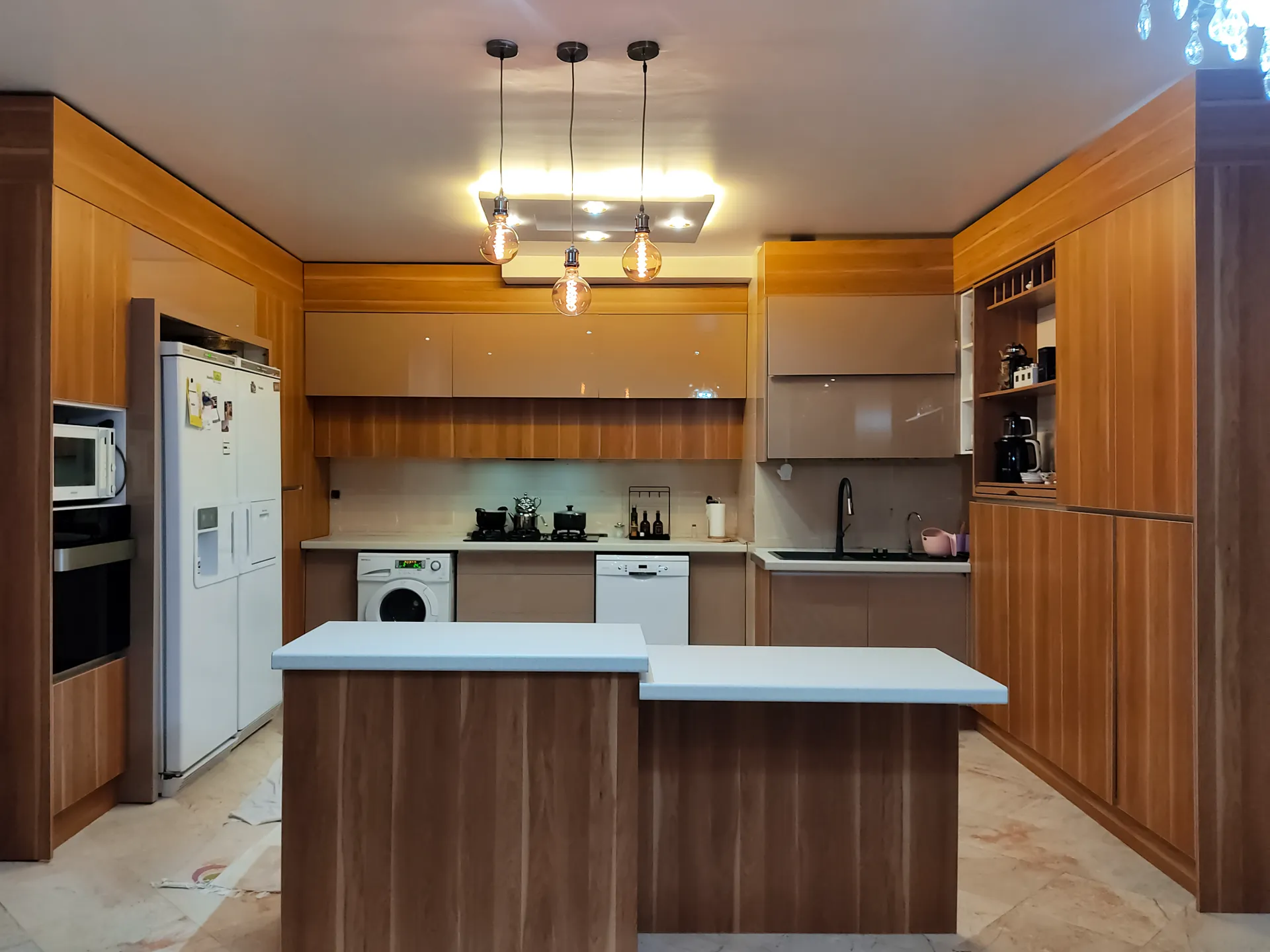 کابینت عسلی با درب‌های حاشیه‌دار و دستگیره‌های نقره‌ای و صفحه کابینت مشکی و چند ردیف کابینت درب ویترینی در یونیت‌های سقفی