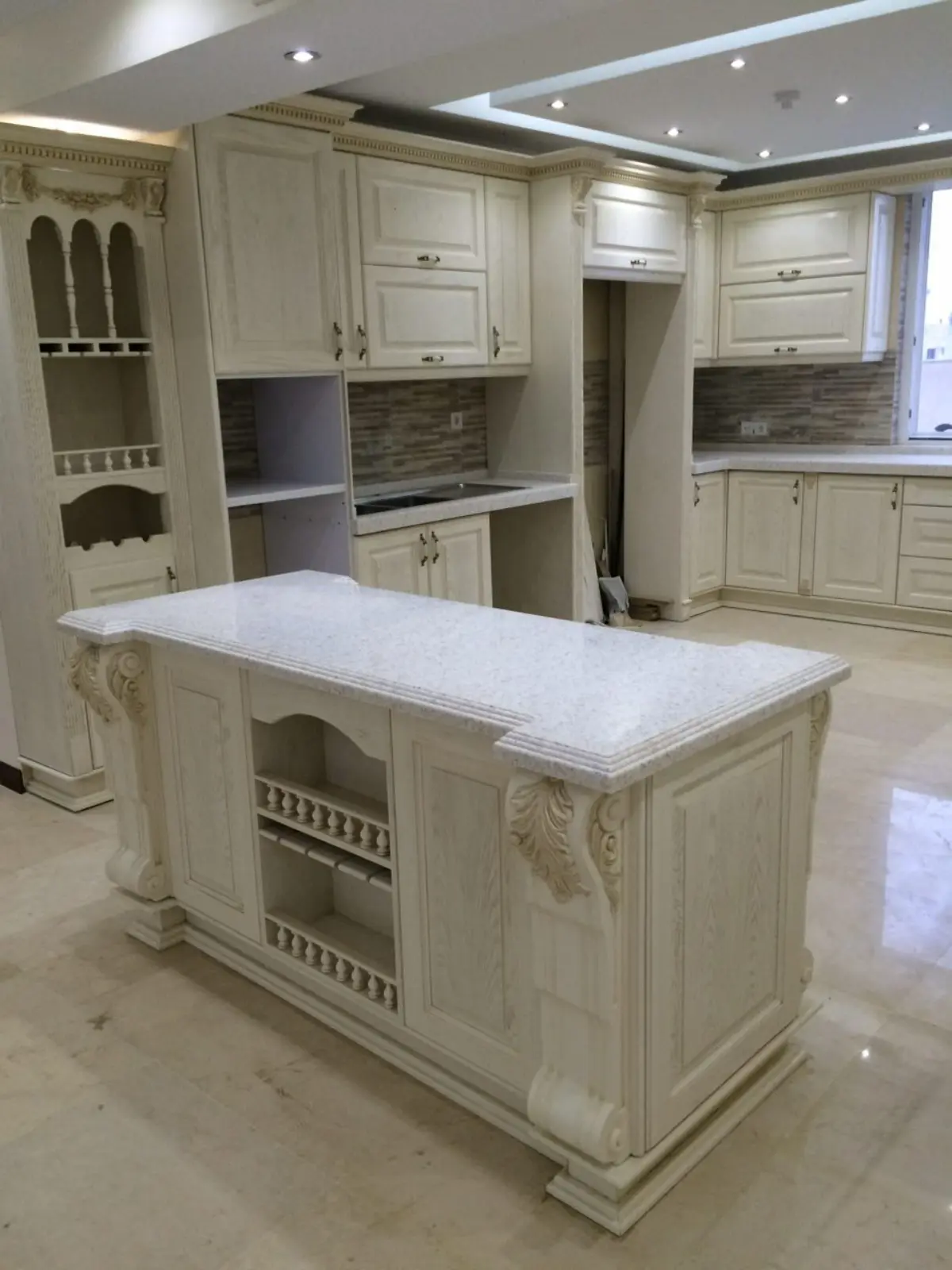 کابینت و جزیره چوبی سفید طلایی با کنده‌کاری روی تاج