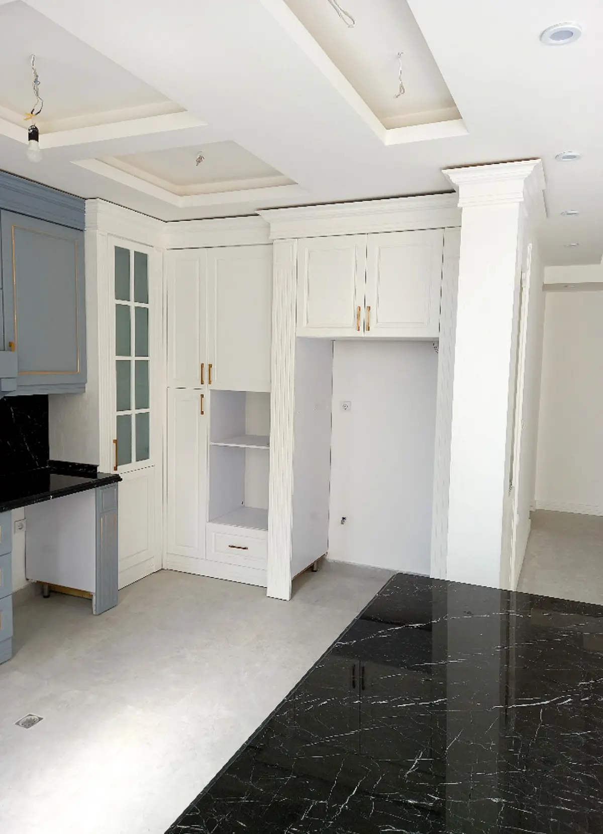 کابینت روکش چوب نئوکلاسیک سفید با دستگیره طلایی و صفحه کابینت مشکی