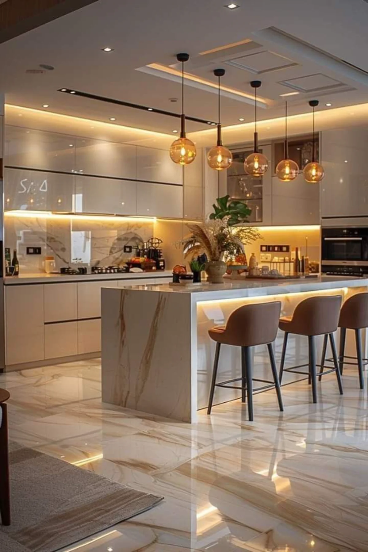 کابینت هایگلاس کرم با اپن جزیره با کاربری ناهار خوری و سه صندلی قهوه‌ای رنگ و چند چراغ حبابی بالای اپن