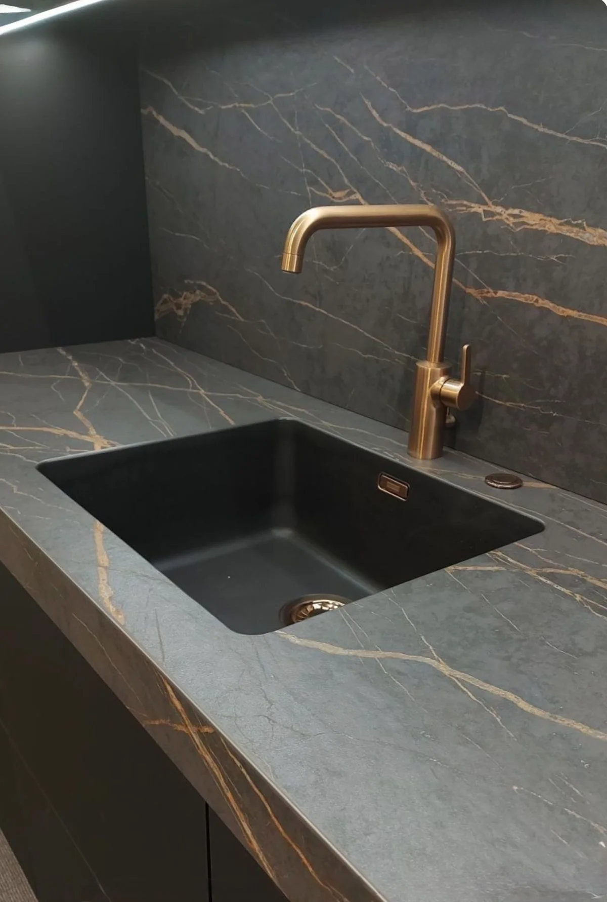 صفحه کابینت پی وی سی مشکی با رگههای طلایی و سینک مشکی با شیر آلات طلایی