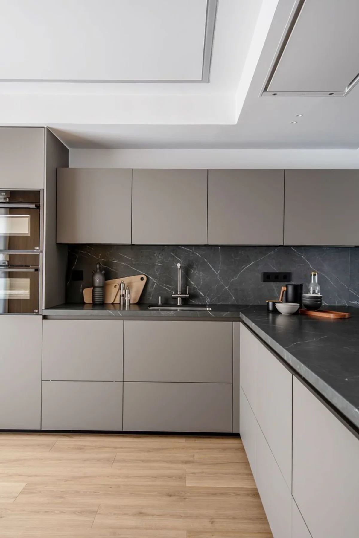 صفحه کابینت پی وی سی مشکی طرح سنگ با رگه سفید و کابینت مدرن طوسی با کابینت کمدی و کف پارکت چوبی