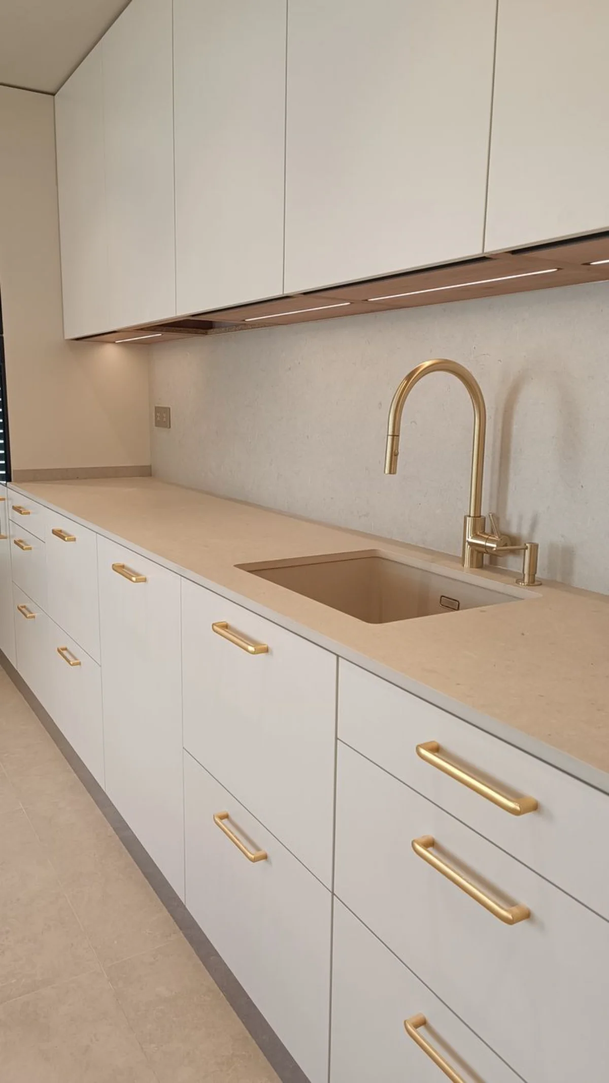 کابینت مدرن سفید با دستگیرههای طلایی و صفحه کابینت پی وی سی کرم طرح چوب ساده