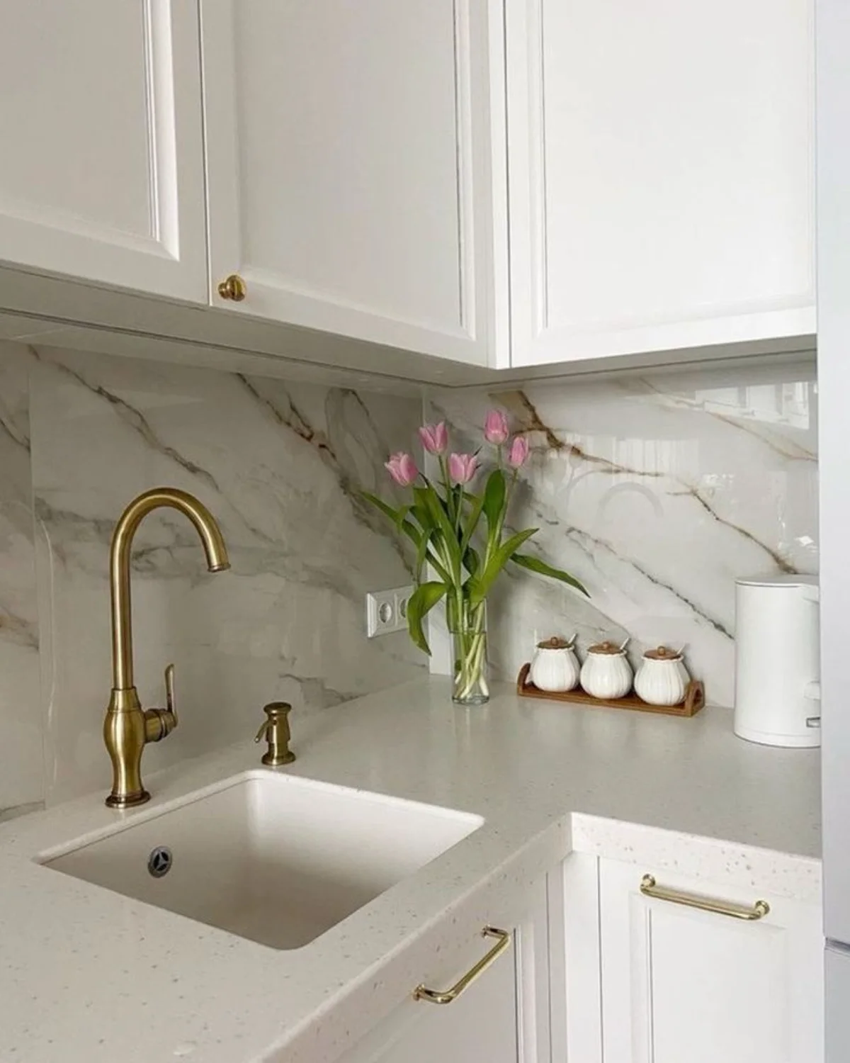 کابینت نئوکلاسیک سفید با صفحه کابینت پی وی سی سفید طرح سنگ و شیرآلات و دستگیرههای طلایی