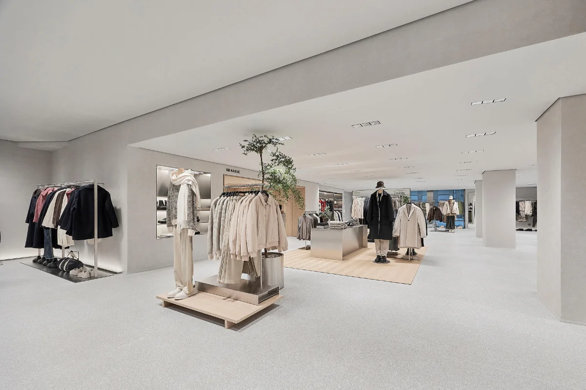 دکوراسیون فروشگاه زارا با چوب لباسی چوبی و دیوار و کف سفید