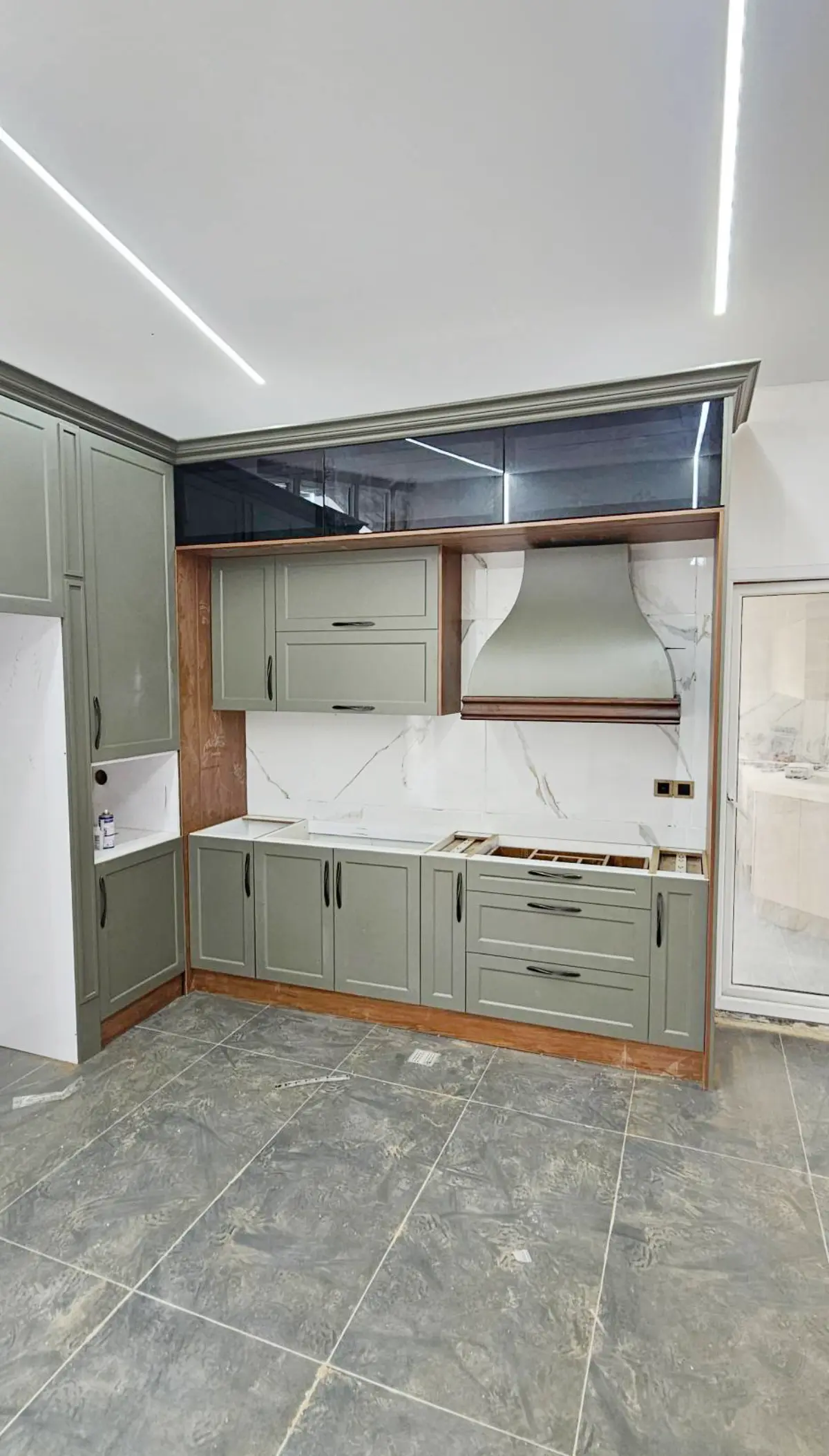 کابینت نئوکلاسیک با رنگ سبز سدری و قهوهای با یک ردیف کابینت ویترینی در بالای یونیتهای دیواری