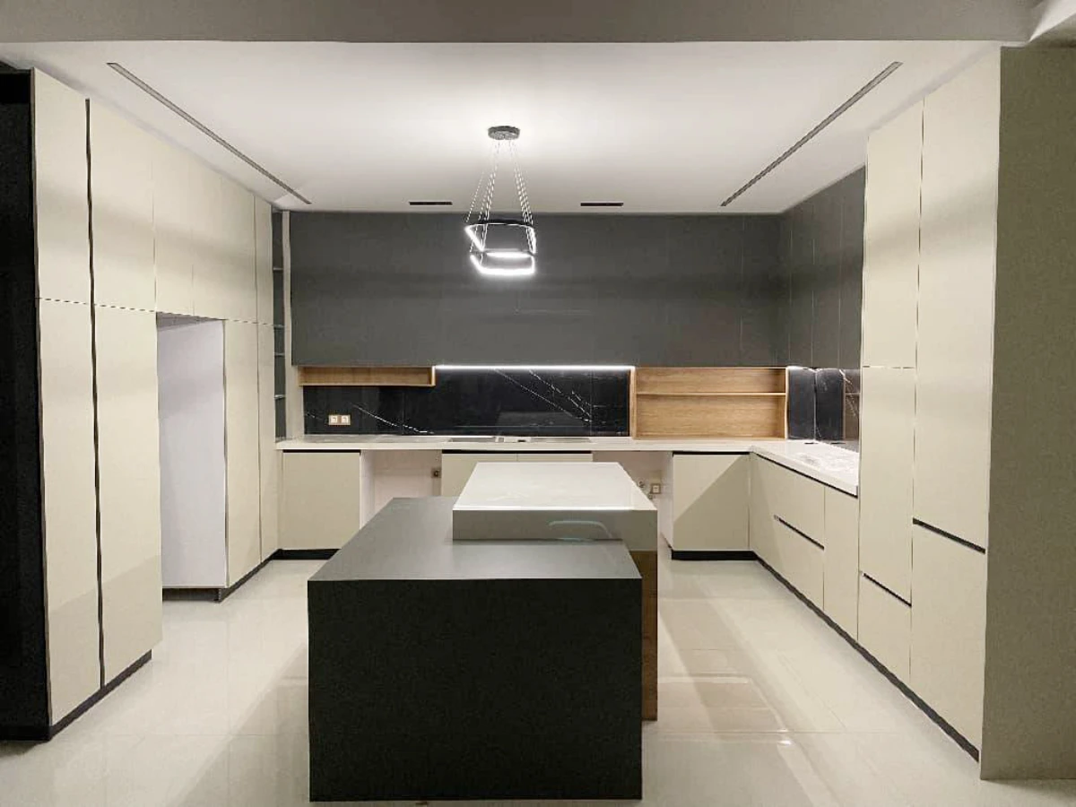 کابینت ام دی اف بژ خاکستری با جزیره مرکزی و پلکانی و لوستر مدرن در بالای جزیره